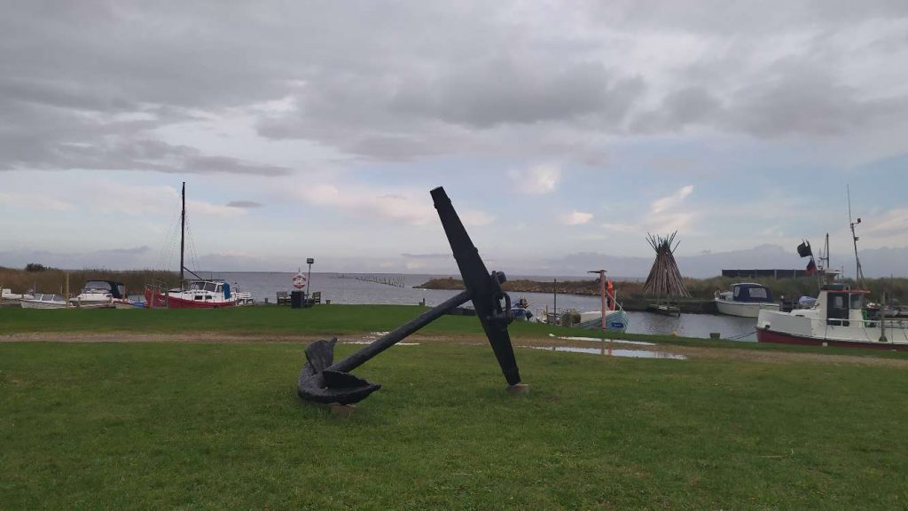 Schiffsanker auf grüner Wiese – Sinnbild für Halt und Erdung
Alt-Text: Schiffsanker auf einer grünen Wiese, Boote und Wasser im Hintergrund – Sinnbild für Erdung, Sicherheit und ein reguliertes Nervensystem
