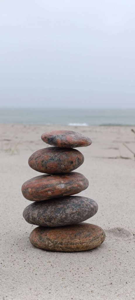 Sorgsam gestapelte Steine am Strand – Symbol für Balance, innere Ruhe und ein zentriertes, reguliertes Nervensystem